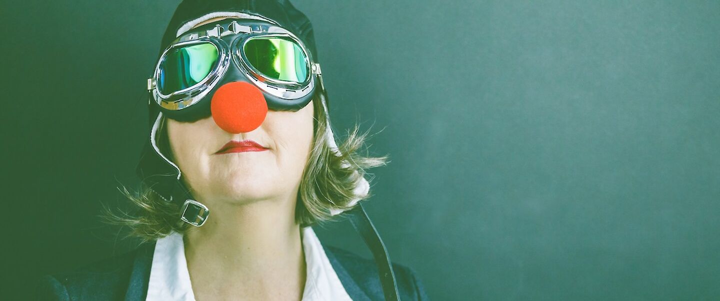 Frau mit Motorradbrille und roter Clownnase